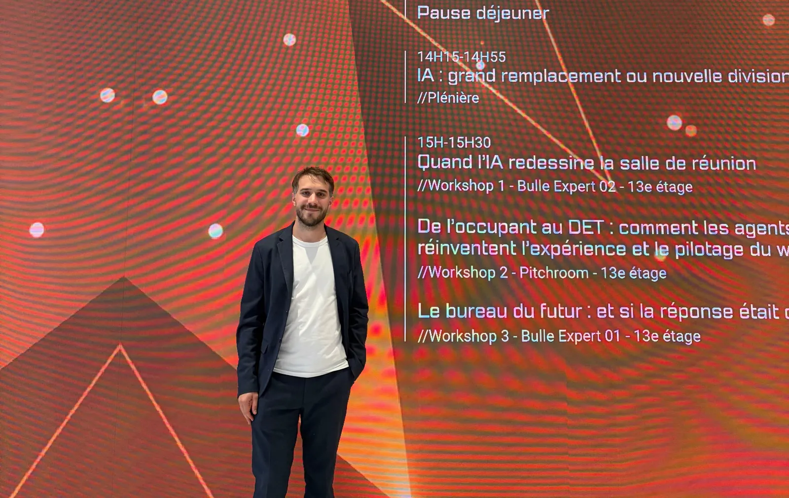 Guillaume Blanc, cofondateur de MerciYanis, devant l'écran du programme de l'IWS 2026 annonçant le workshop sur les agents IA et le pilotage du workplace