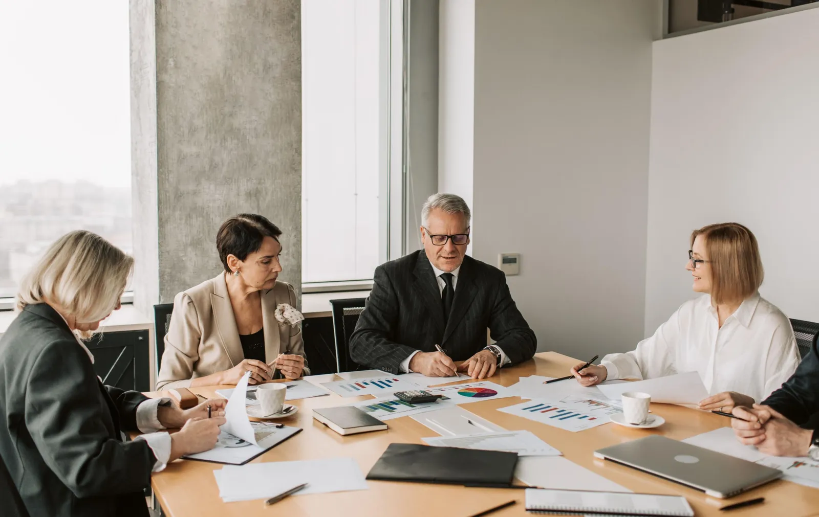 Équipe en réunion analysant des tableaux de données pour préparer un appel d'offres Facility Management