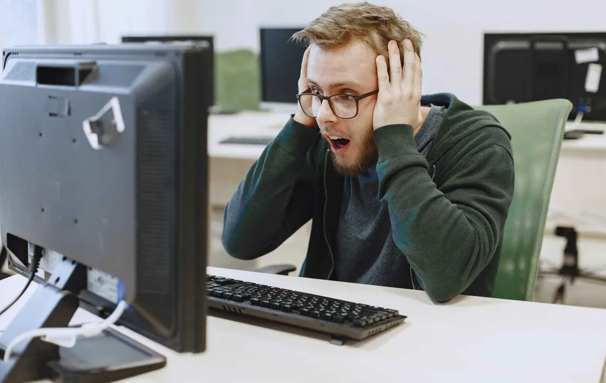 Un homme stressé se tient la tête devant son écran — la déclaration OPERAT vécue comme une course contre la montre