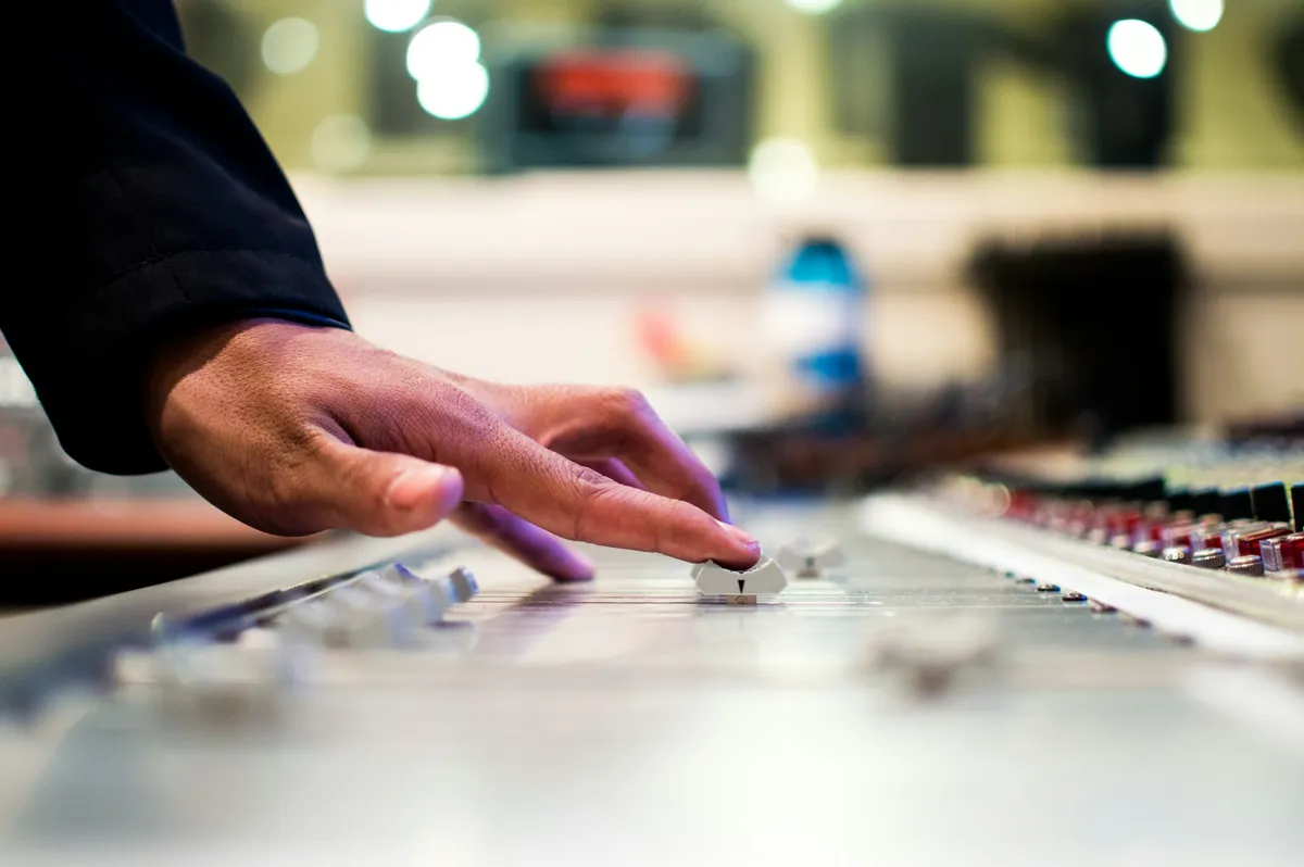 Une main ajuste un curseur sur une console de mixage — réviser le taux de foisonnement à mesure que les usages évoluent