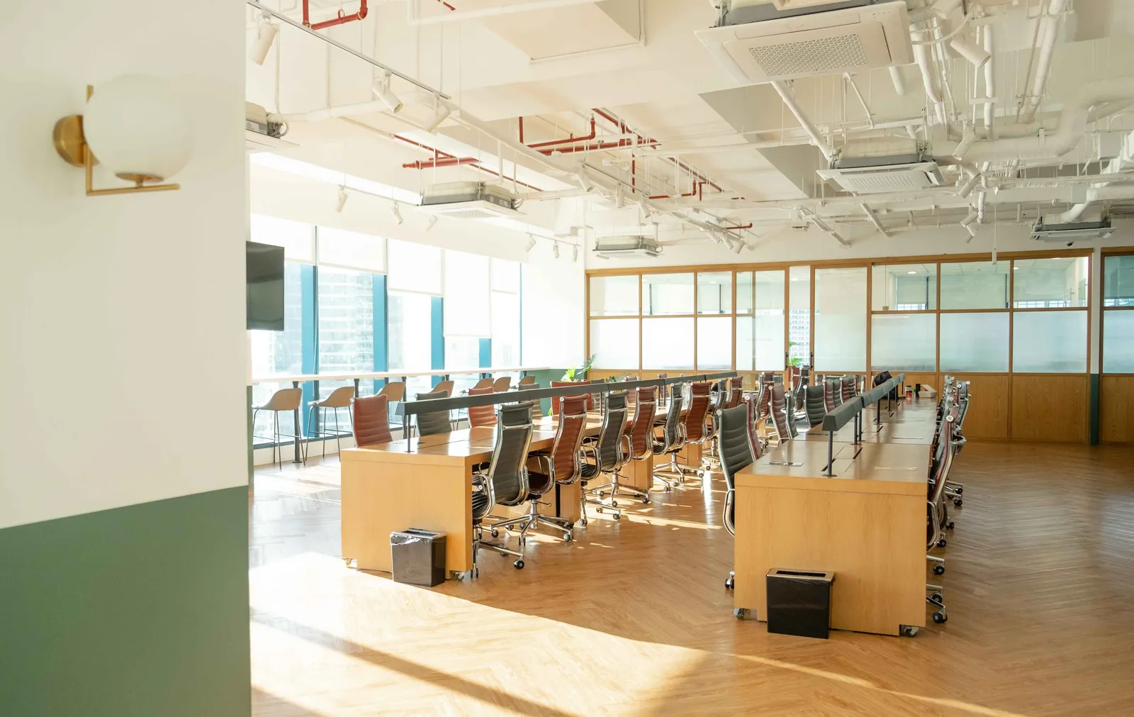 Vaste open space avec de longues rangées de postes de travail et de fauteuils, symbole du flex office