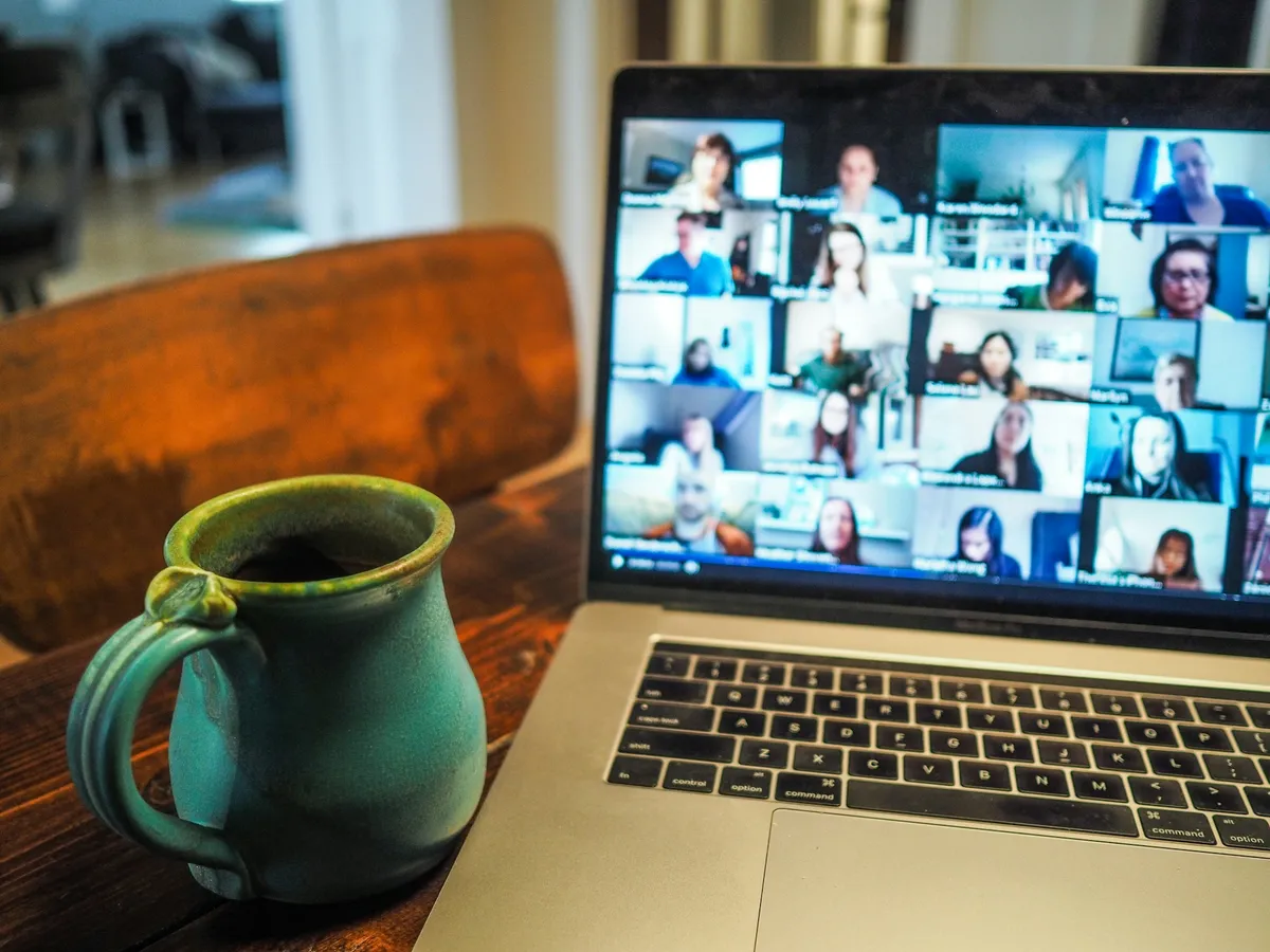 Ordinateur portable affichant une visioconférence à nombreux participants, à côté d'une tasse — le télétravail et l'hybridation
