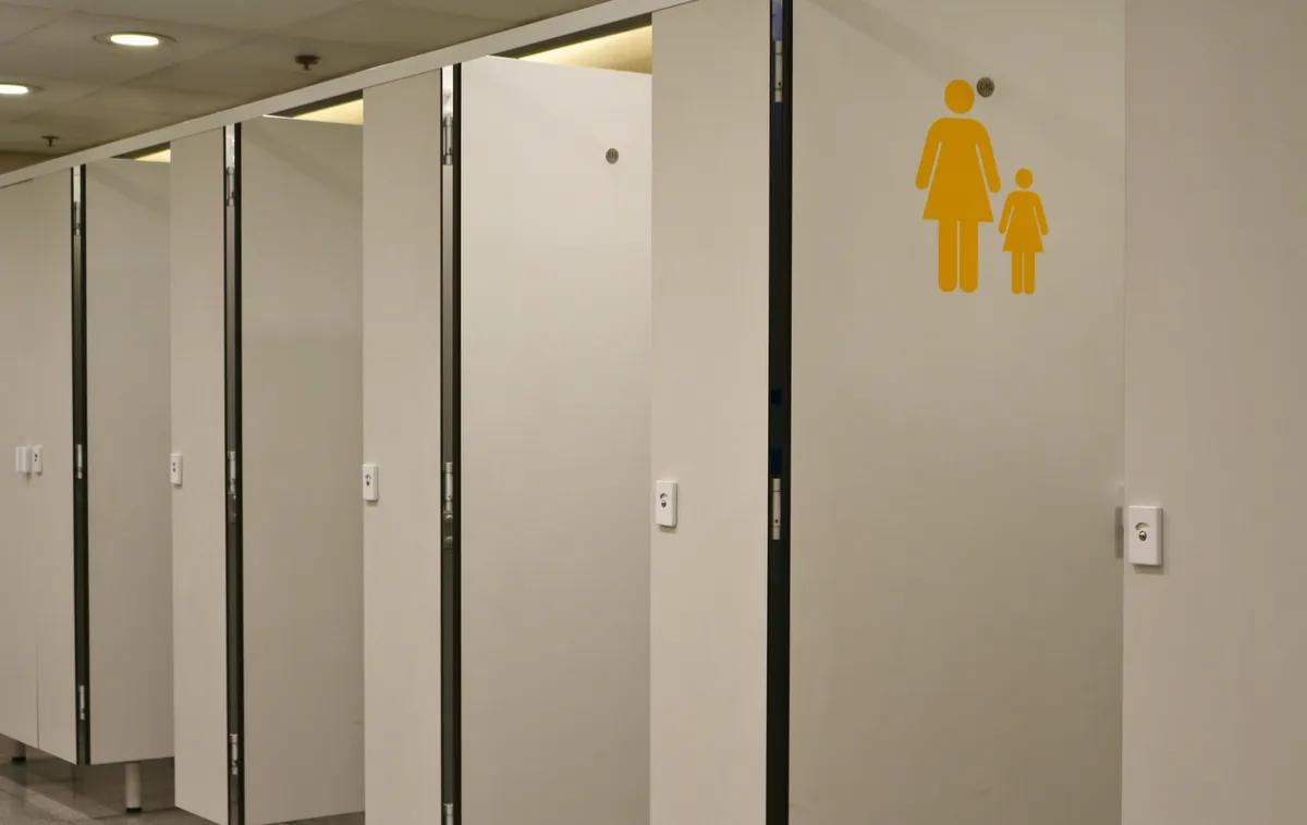 Un bloc sanitaire d'entreprise avec ses cabines fermées et un pictogramme de signalétique sur le mur