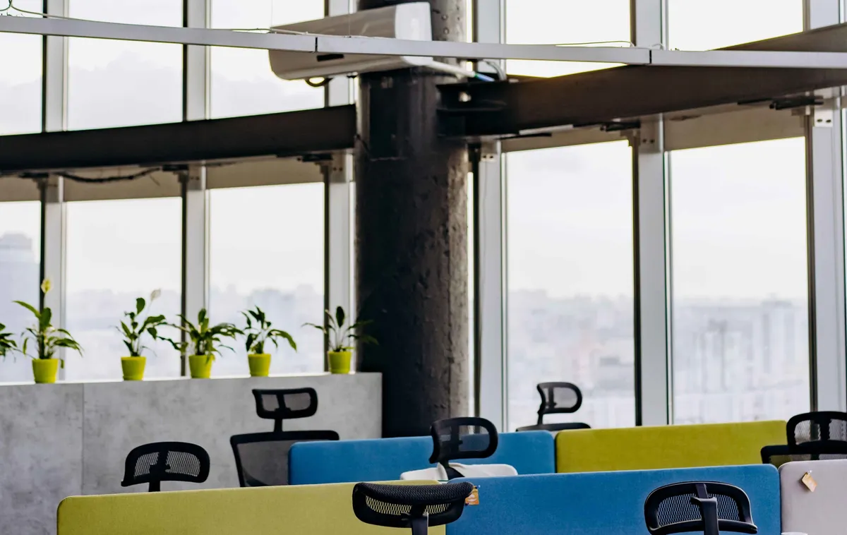 Open space aux grandes baies vitrées, plantes et postes de travail — la qualité de l'air dans les bureaux