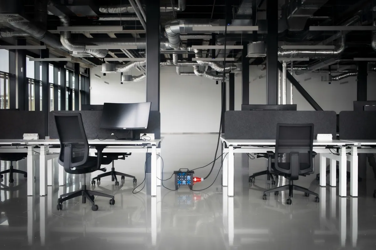 Un open space entièrement vide : bureaux, écrans et sièges inoccupés sur un plateau de bureaux