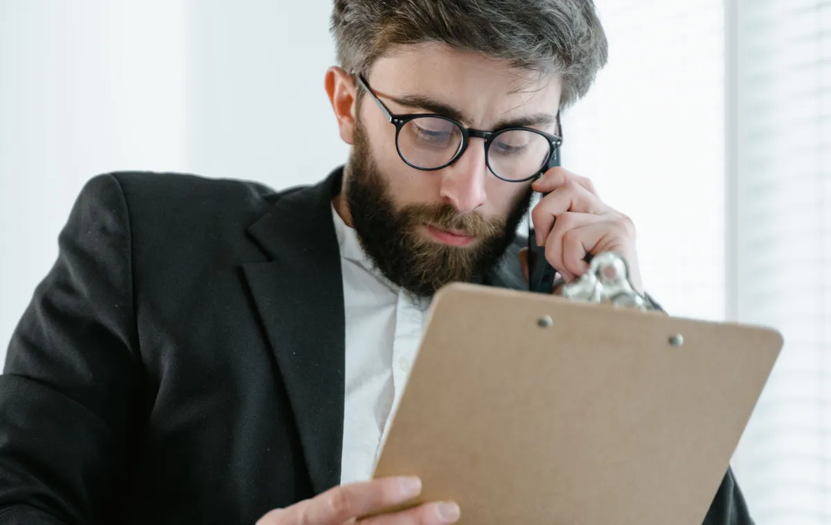 Un responsable des services généraux au téléphone vérifie le planning de ses prestataires sur un porte-bloc